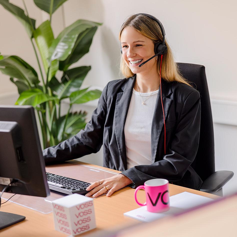 VOSS Benefits Flexible Arbeitszeitmodelle Junge Frau unterhält sich mit ihrem Arbeitskollegen und hält eine Tasse Caffè in der Hand